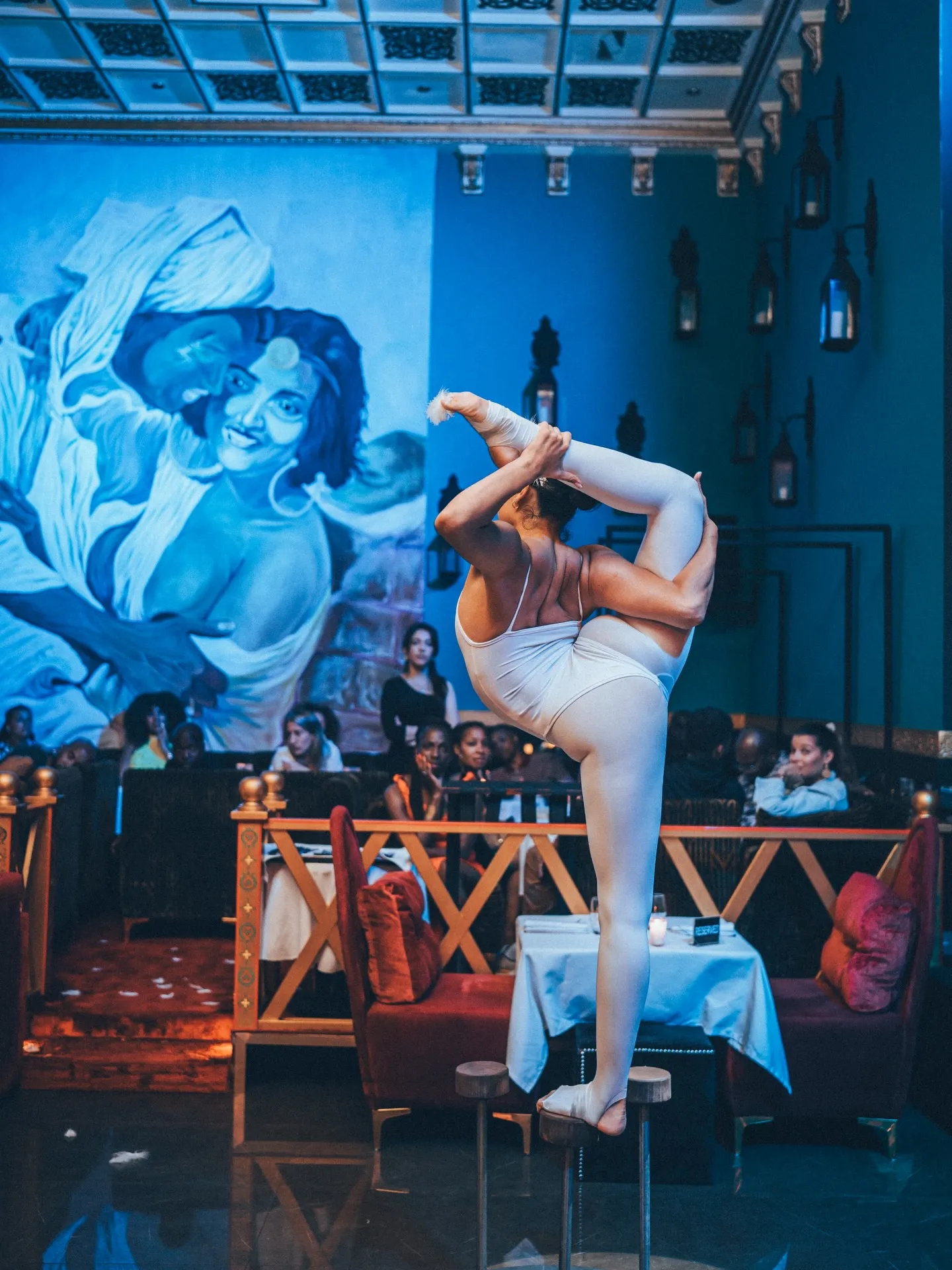 Contortionist performing against the blue mural above the dining room at LOV