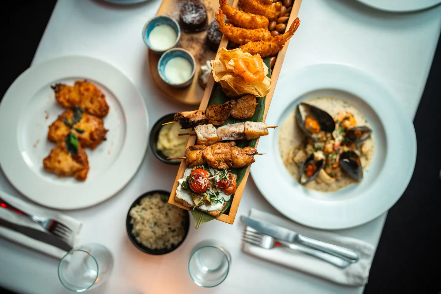 Overhead view of a sharing table at LOV with skewers, dips and small plates
